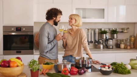 Happy couple drinking wine and cooking in kitchen