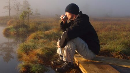 Hiker drinking coffee by marsh