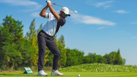 Man swinging golf club in fairway