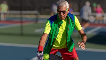 Senior man playing pickleball with sunglasses