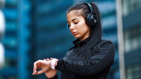 Woman checking smartwatch jogging in city
