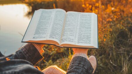 Woman reading bible outdoors at sunset