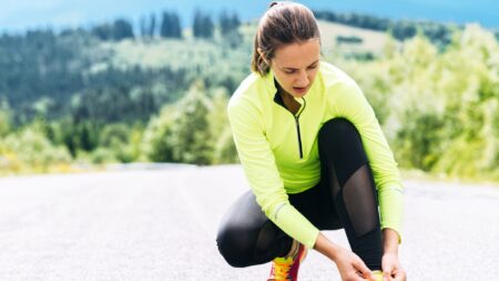 Woman runner tying shoe on road