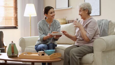 Woman serving dinner to senior in living room