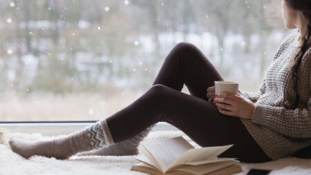 Woman with book and coffee mentally preparing for winter