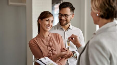 Young couple buying home getting keys from realtor