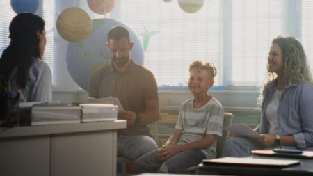 Young student and parents talking with teacher at school