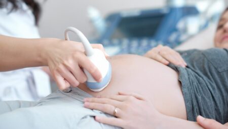 Doctor using ultrasound equipment screening of pregnant woman.