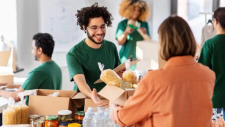 happy volunteers packing food in donation boxes