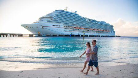 Middle aged couple enjoying a Caribbean Cruise vacation together. Candid photo of a couple holding hands and walking together on a beach with a Cruise ship in the background