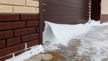 A brick wall with a snow covered garage door
