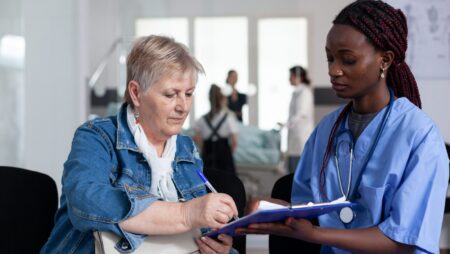 Sick old lady filling out files in hospital waiting room