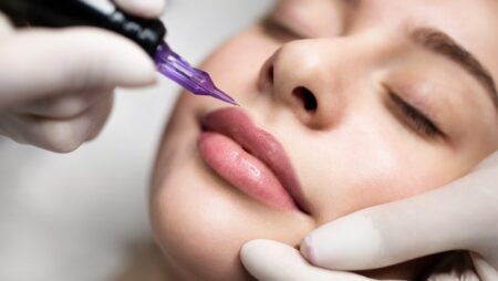 PMU Concept. Permanent Makeup Artist Doing Lip Blushing Procedure To Young Woman