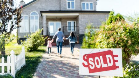 family moving into new house with sold signboard on