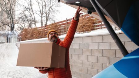 Man buying christmas gifts during winter, bringing box home. Mature man moving to the new house, packing into cardboard box.