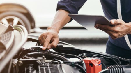 Auto mechanic under hood of vehicle