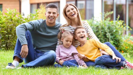 Happy family sitting in grass in front of home