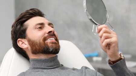 Man at dentist smiling into mirror