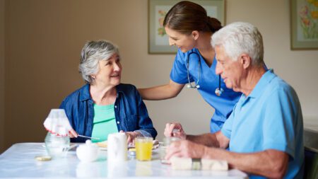 Seniors eating breakfast at retirement home with nurse