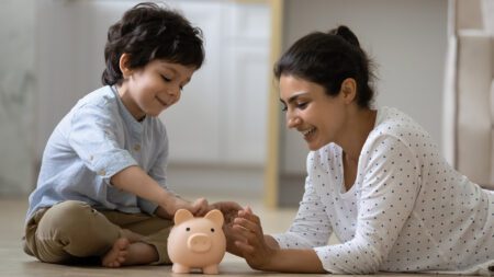Mom and son putting money into piggy bank