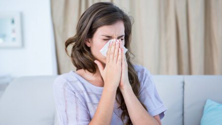 Sick woman sneezing and blowing nose