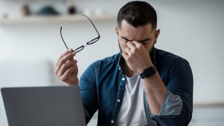 Tired man rubbing eyes and holding glasses