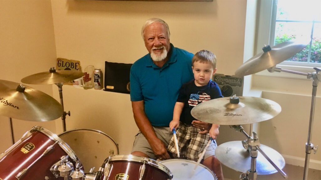Dave Holly sitting behind the drums with Nolan's son Cole, taking the time to teach him a little about playing - Discover NC Homes