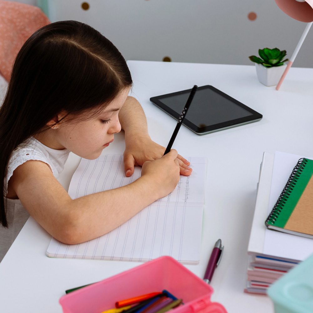 Young girl writing at table Merry Maids (Canterbury)