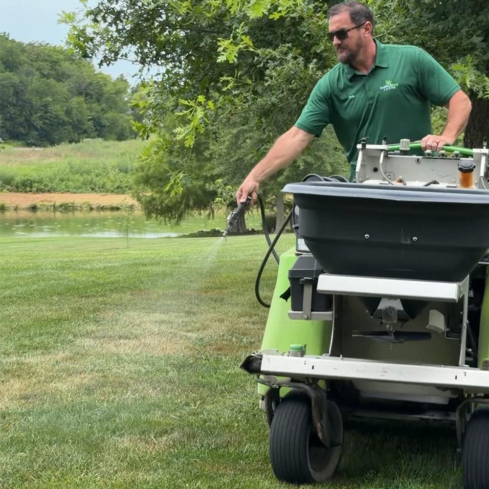 Worker spraying grass Emerald Edge Lawns